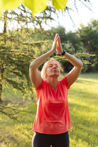 Rear view of young woman exercising on field