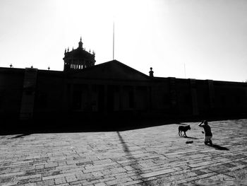 Silhouette man against built structure against clear sky