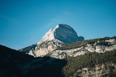 Low angle view of rocky mountain against blue sky