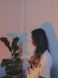 Portrait of young woman standing against wall