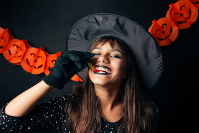 Portrait of young woman wearing mask against black background