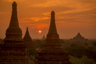 Stupas against dramatic sky during sunset