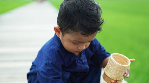 Cute boy holding container outdoors