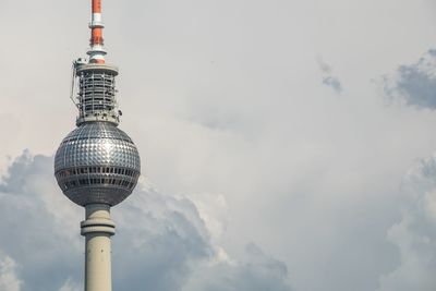 Low angle view of fernsehturm against cloudy sky