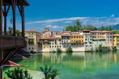 Buildings by river against sky