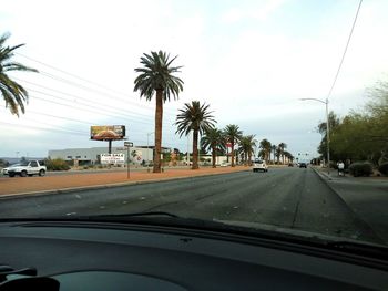 Cars on street against sky seen through car windshield
