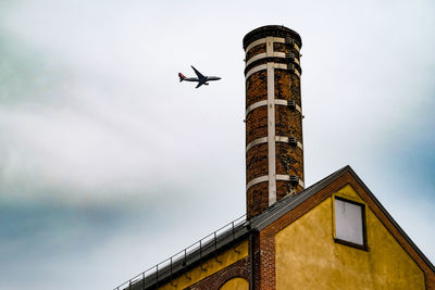 Low angle view of airplane flying in building against sky