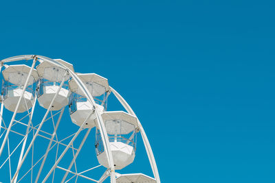 Low angle view of ferris wheel against clear blue sky