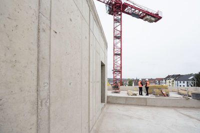 Two men wearing safety vests talking on construction site