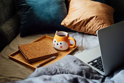 Cozy home, autumn warm mood. laptop, notebook and cup of tea at tray on blanket in bed in the