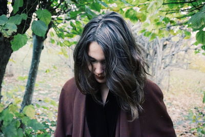 Close-up of young woman standing against trees