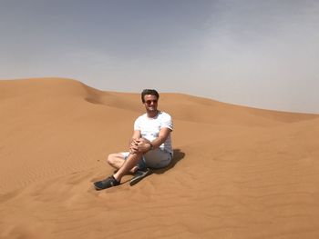 Full length of man on sand in desert against sky