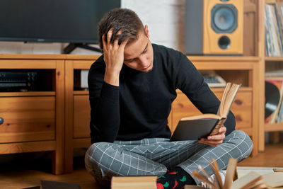 Man reading book while sitting on floor at home