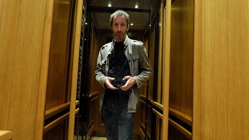 Portrait of man photographing while standing in front of mirror