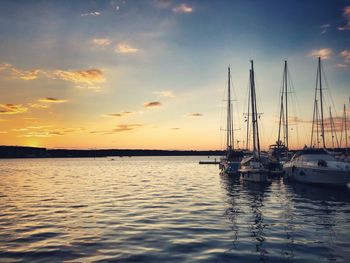 Sailboats in sea at sunset