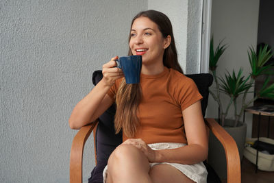 Portrait of young woman sitting on sofa at home