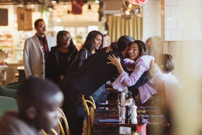 Multiracial male and female friends greeting at restaurant afterwork