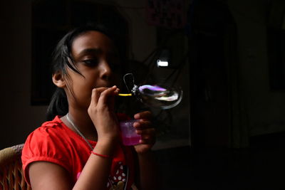 Girl blowing bubbles while sitting at home