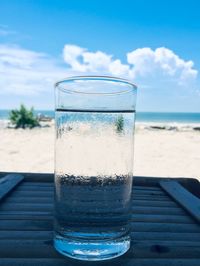 Close-up of drink on table at beach against sky