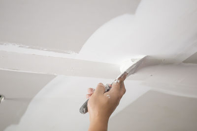 Cropped hand of person applying putty on wall