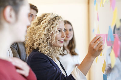 Colleagues in office at glass pane with adhesive notes