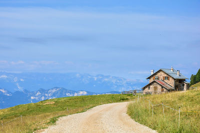 Scenic view of field by houses against sky