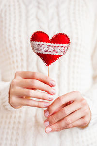 Woman in knitted sweater holding felt red heart. bright red symbol of love and valentine day.