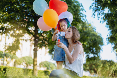 Mother and daughter having fun on girl birthday hugging near city fountain