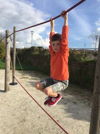 Full length of boy hanging at jungle gym