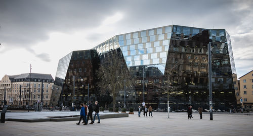 People on modern buildings in city against sky