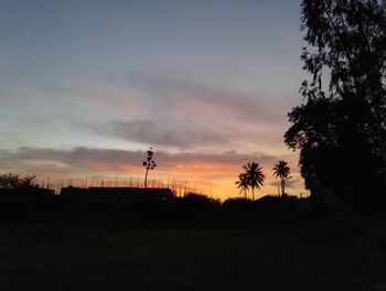 Silhouette trees on landscape against sky at sunset