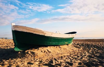 Boat moored on beach against sky