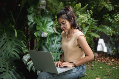 Young woman using mobile phone while sitting outdoors