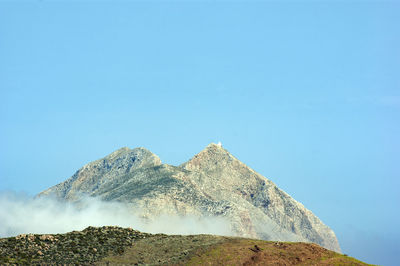 Low angle view of rocky mountain against blue sky