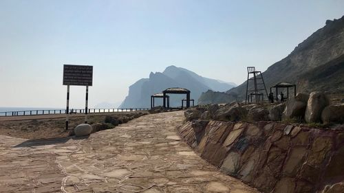Footpath amidst rocks and buildings against clear sky