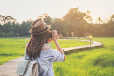 Rear view of woman photographing on field