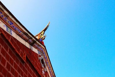 Low angle view of red building against clear blue sky