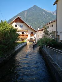 Houses by river and buildings against sky