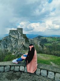 Rear view of woman sitting against wall