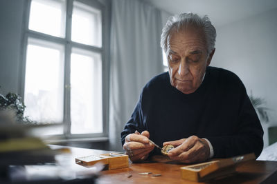 Senior man repairing a watch at home