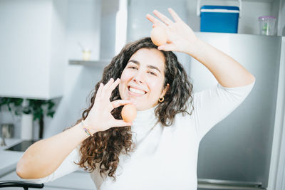 Portrait of smiling woman holding food in kitchen