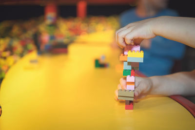 Cropped hands of child playing with toy blocks on table