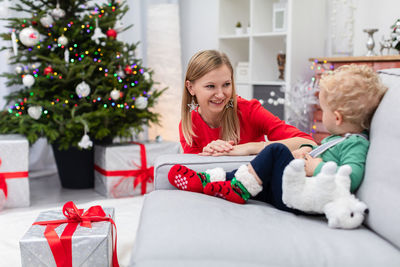 Portrait of mother and daughter sitting on sofa at home