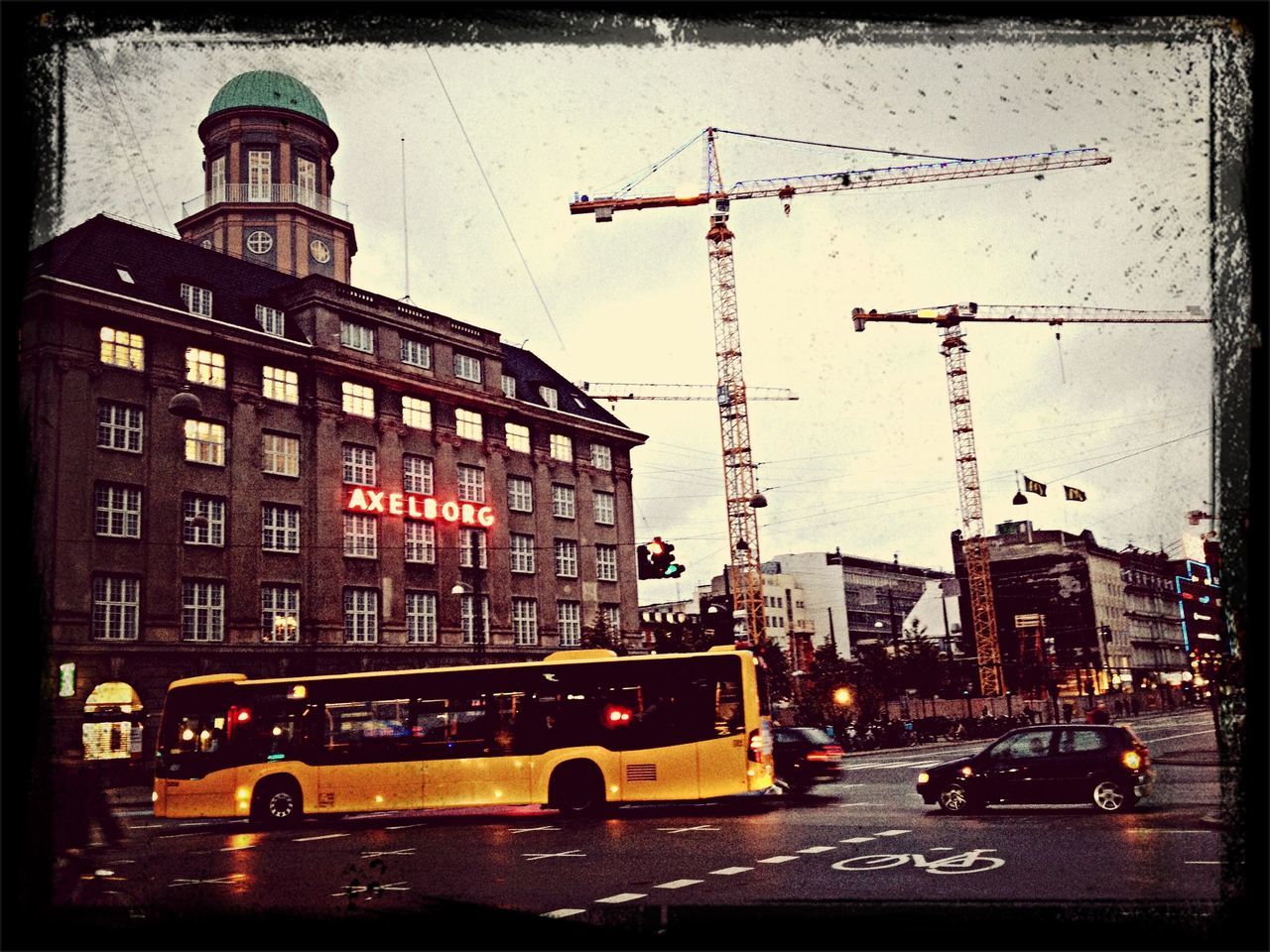 transportation, building exterior, architecture, car, mode of transport, land vehicle, built structure, city, street, traffic, road, city life, city street, travel, on the move, street light, sky, building, tower, incidental people