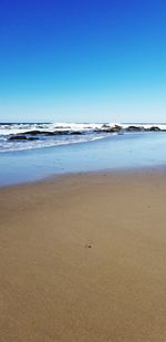 Scenic view of beach against clear blue sky