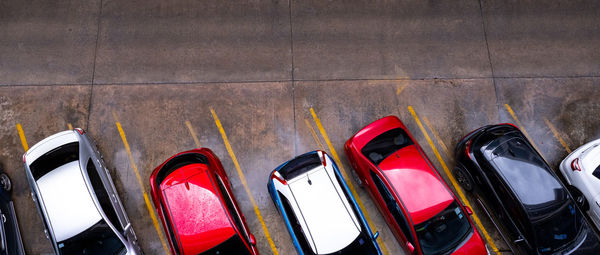 Top view of car parked at concrete car parking lot with yellow line of traffic sign on the street.