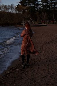 Rear view of woman walking on sand