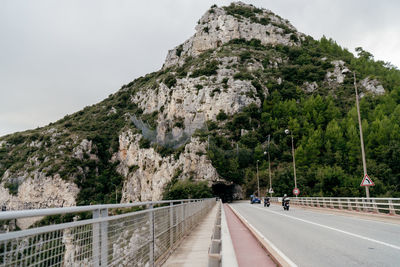 People on road by mountain against sky