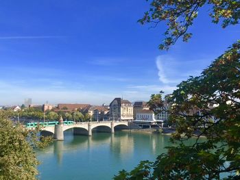 Arch bridge over river against blue sky in city