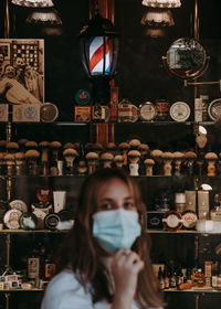 Portrait of woman standing in front of barbershop window with focus on the background